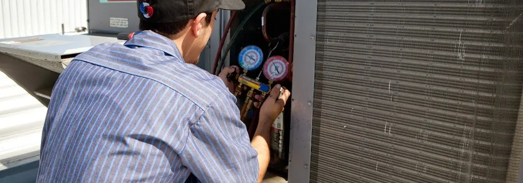 HVAC technician servicing a condenser unit in Royalton